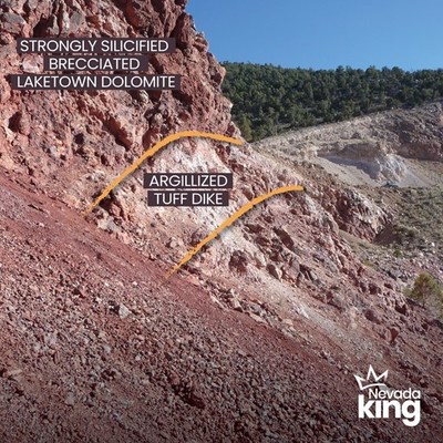 Figure 6. View to south at southern end of Atlanta pit of strongly silicified and argillized felsic tuff dike dipping steeply eastward and cutting across near-horizontal, densely silicified and brecciated Laketown Dolomite. The silicified rock has a greenish color, but hematite in breccia voids imparts an overall reddish tint. (CNW Group/Nevada King Gold Corp.)
