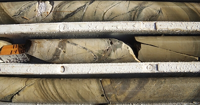 Figure 5: Great Pyramid diamond core (22GPDD008, 123m). Interbedded sandstone and siltstone with multiphase quartz-sulphide veins (sulphides dominated by arsenopyrite-pyrrhotite-pyrite) associated with biotite, chlorite and sericite alteration.  Diamond drill hole beneath historic resource area, assay results pending. (CNW Group/TinOne Resources Corp.)