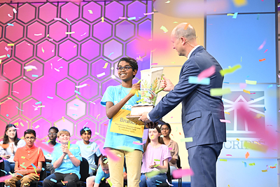 2024 Scripps National Spelling Bee Champion Speller 47 Bruhat Soma of St. Petersburg, FL, representing Rays Baseball Foundation and Rowdies Soccer Fund, receives the Scripps Cup from Adam Symson, President and CEO of The E.W. Scripps Company, in National Harbor, MD, on Thursday, May 30, 2024. 
ph: Edward M. Pio Roda / Scripps National Spelling Bee.