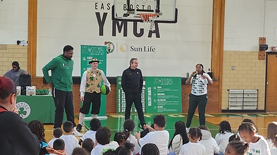 Leon Powe and Lucky the Leprechaun, along with president of Sun Life U.S., David Healy, talk to kids about fitness and healthy living at the launch of annual Sun Life and Boston Celtics Fit to Win program at East Boston YMCA.