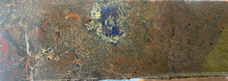 Figure 1: &nbsp;Hole DCKDH005 - ~395 metres – Drill core with blebs of bornite rimmed by epidote and carbonate hosted in feldspar-sericite-tourmaline-actinolite-pyrite altered volcanics.