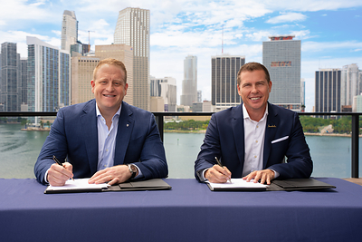 Jason Liberty, Chairman and CEO of Royal Caribbean Group, and Adam Stewart, Executive Chairman of Sandals Resorts, mark the signing of an agreement to form a landmark partnership that expands Royal Caribbean Group into the all-inclusive resort space and supports the future growth of Sandals and Beaches Resorts. The signing took place at Royal Caribbean Group's new headquarters in Miami, with the city's skyline in the background.
