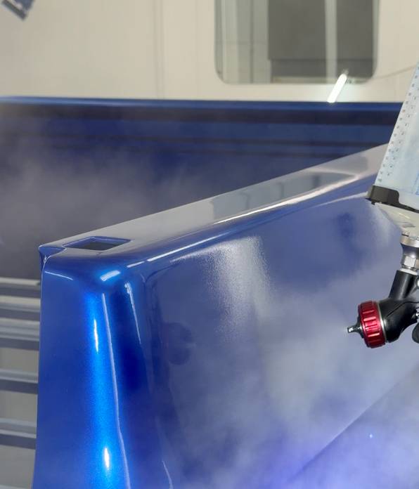 Close-up of blue paint being sprayed onto a Project REBORN-001 body panel